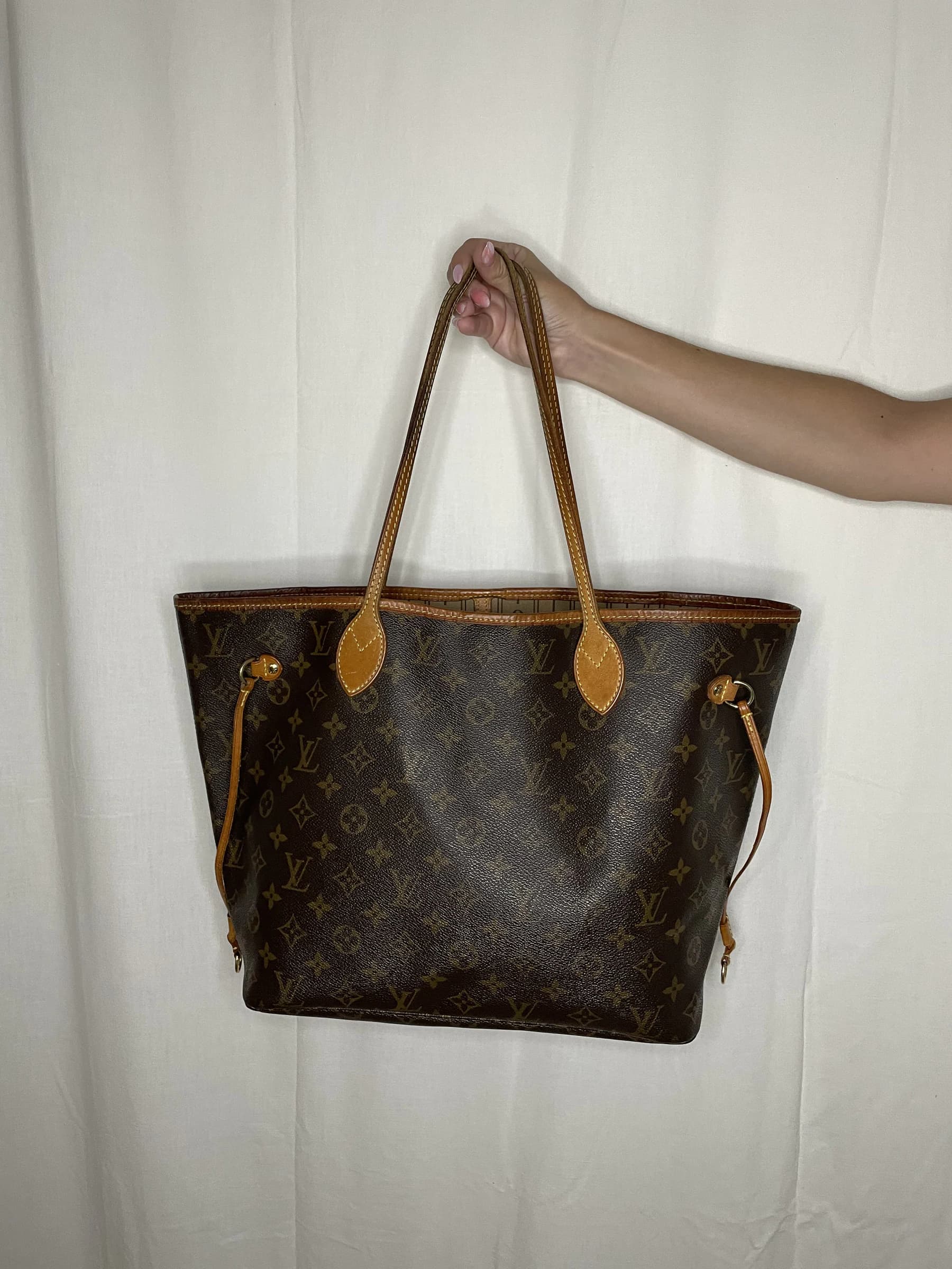 Sac Neverfull présenté de face, tenu par ses anses